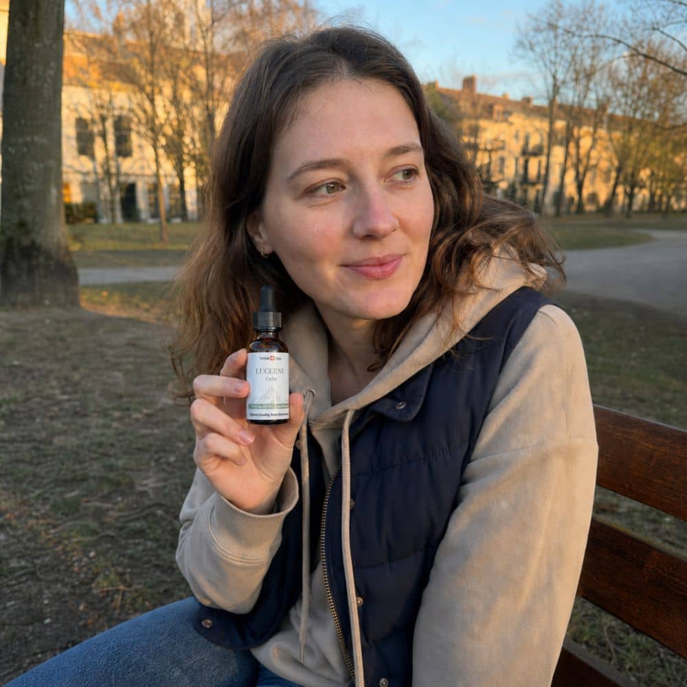 Mujer sosteniendo una botella de aceite de CBD de Lucerna al aire libre en un parque