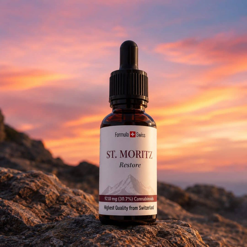 Formula Swiss St. Moritz Restore CBD oil bottle displayed on mountain rocks beneath a vivid sunset sky.